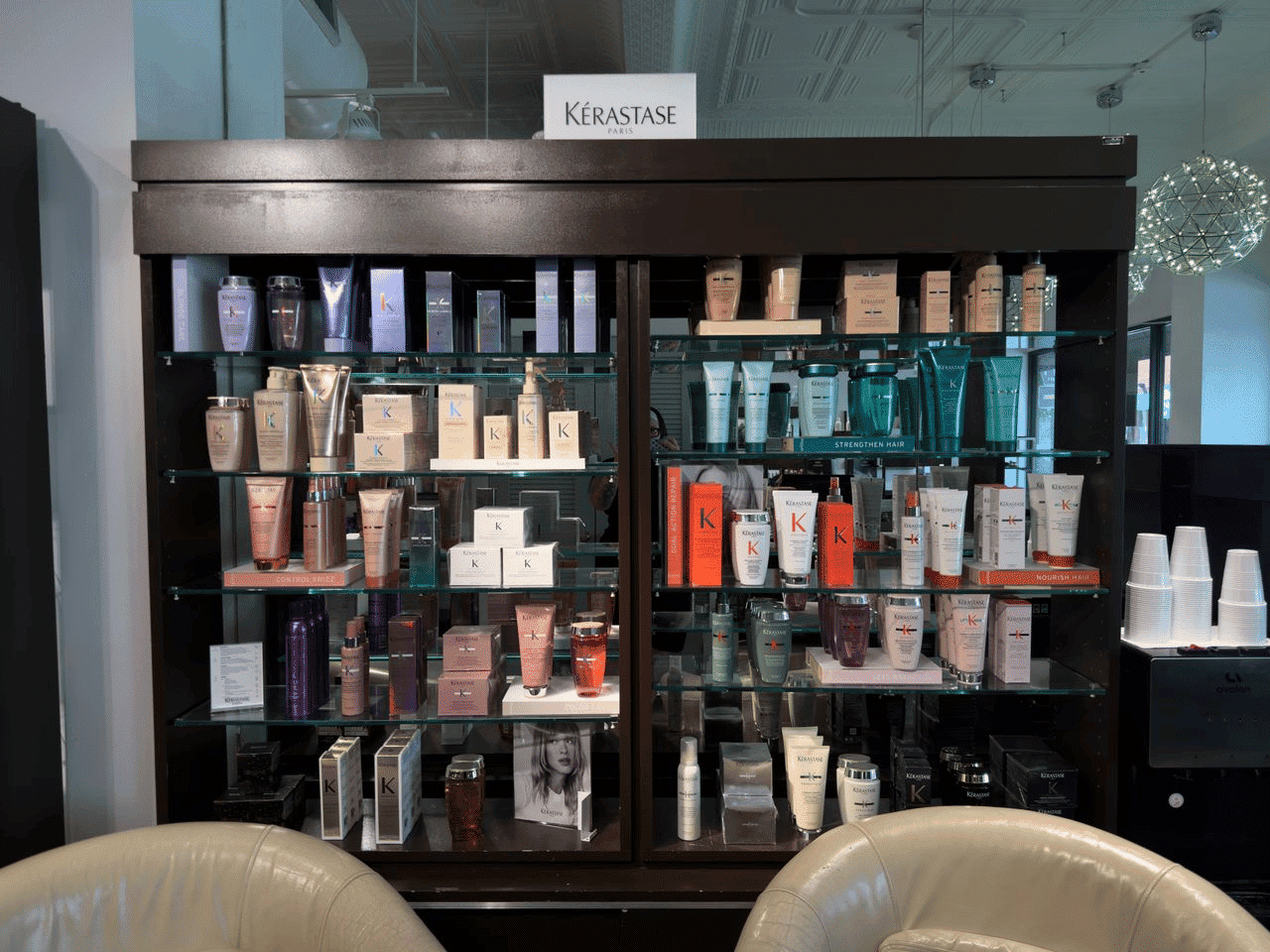 Kerastase products displayed on shelves in a salon with modern decor and seating area.