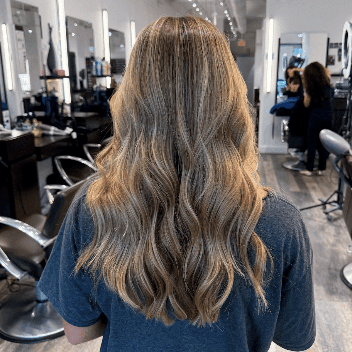 Person with long, wavy blonde hair in a salon.