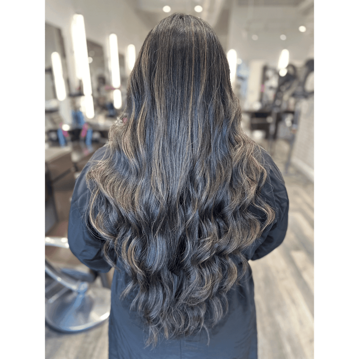 Long wavy hair with highlights in a modern salon setting.