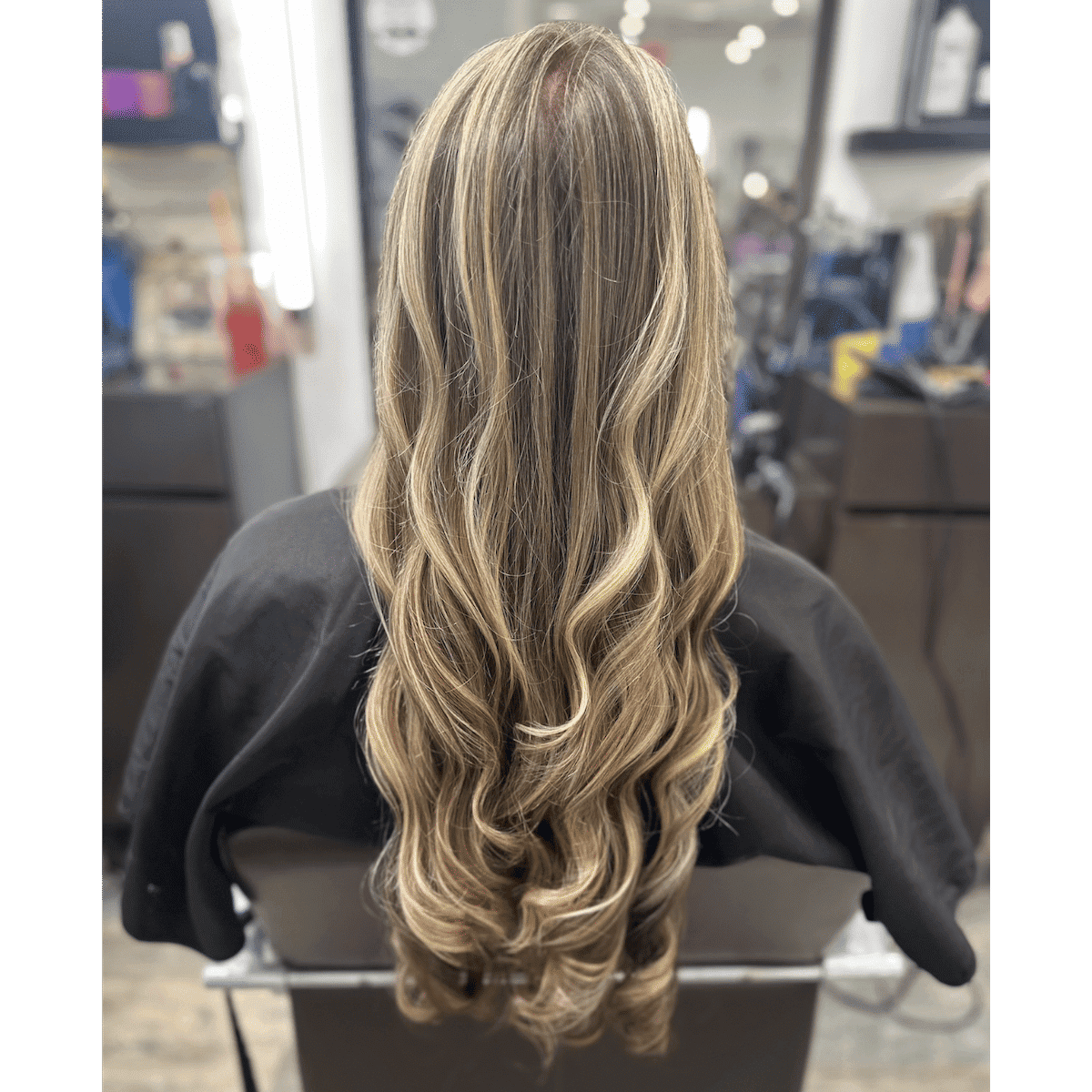 Long, wavy blonde hair with highlights, styled at a salon.