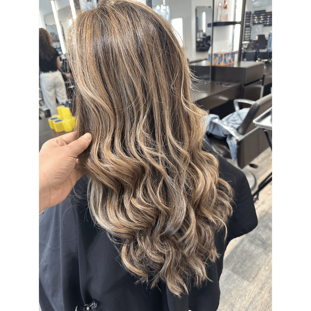 Long wavy hair with blonde highlights in a salon setting.