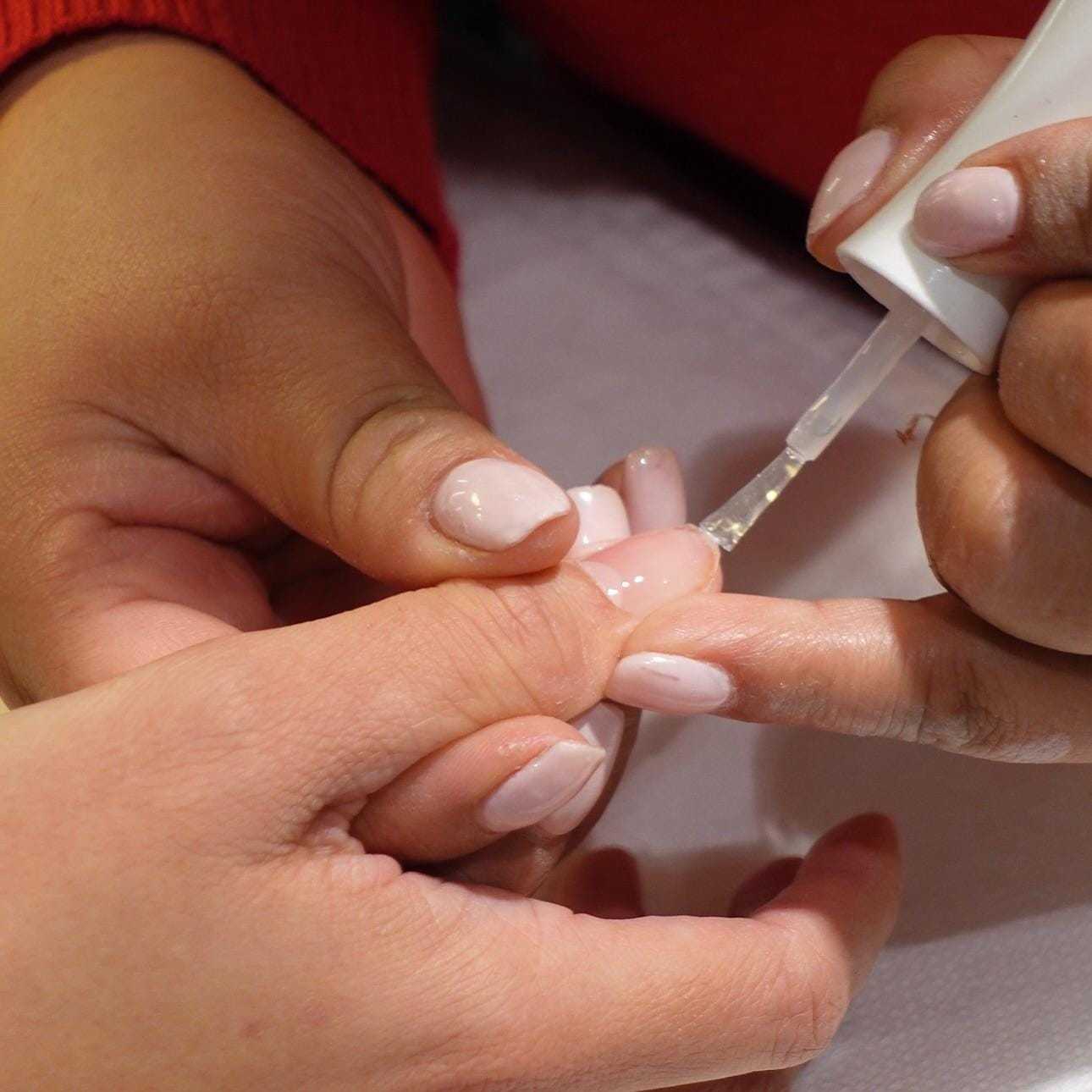 Applying light pink nail polish during a manicure.